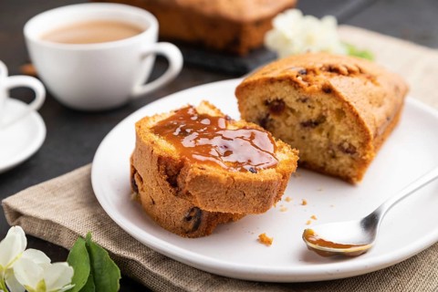 Homemade cake with raisins, almonds, soft caramel and a cup of coffee on a black concrete