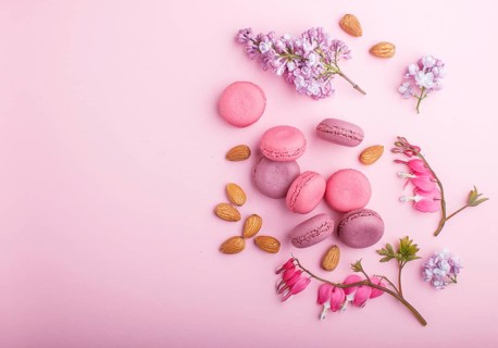 Purple and pink macaron or macaroon cakes with lilac and bleeding heart flowers on pastel pink