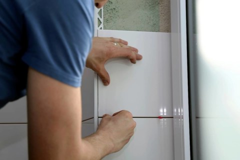 Tiler lays tiles on the wall