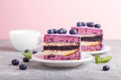 Homemade cake with souffle cream and blueberry jam with cup of coffee and fresh blueberries on gray