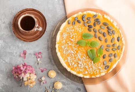 Traditional american sweet pumpkin pie decorated with mint, sesame and pumpkin seeds with cup of