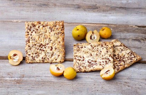 Biscuits with flax, sesame and sunflower seeds and yellow quince fruit on a rustic wooden