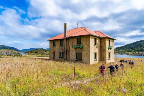 Hikers in front of the museum at a historic Yaghan aboriginal settlement, Wulaia Bay, Navarino