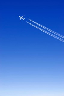 A passenger plane with vapour trails high in the blue sky