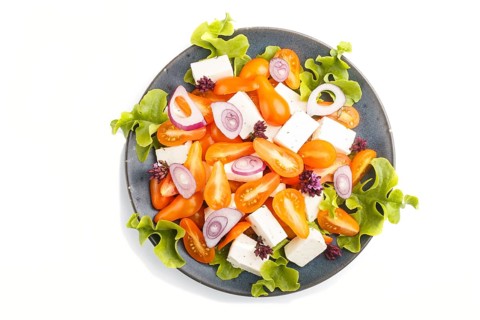 Vegetarian salad with fresh grape tomatoes, feta cheese, lettuce and onion on blue ceramic plate