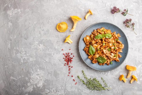 Fried chanterelle mushrooms with basil and spice herbs on gray concrete background. Top view, flat