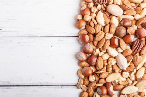 Mixed different kinds of nuts on white wooden background. hazelnut, brazil nut, almond, pumpkin