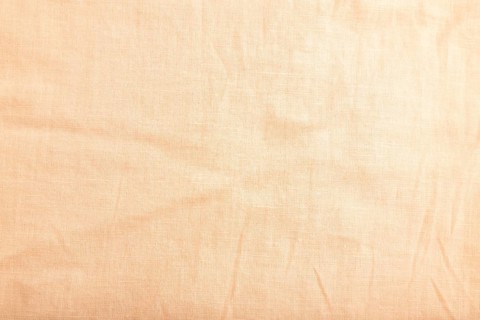 Fragment of smooth orange linen tissue. Top view, flat lay, natural textile background and texture