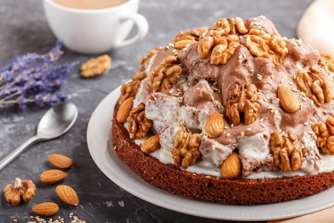 Homemade cake with milk cream, cocoa, almond, hazelnut on a black concrete background with orange