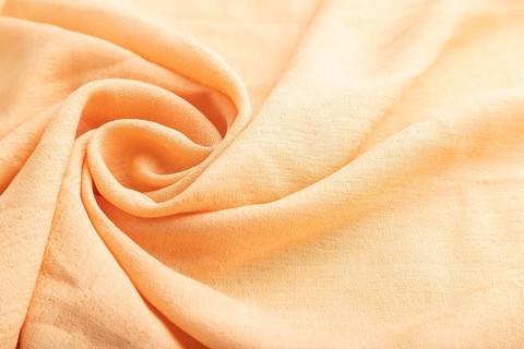 Fragment of orange linen tissue. Side view, natural textile background and texture. wave concept,