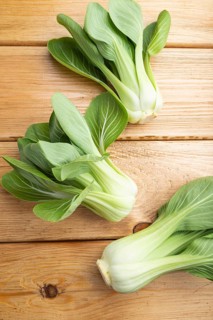 Fresh green bok choy or pac choi chinese cabbage on a brown wooden background. Top view, close up,