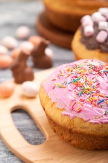 Homemade glazed and decorated easter pies with chocolate eggs and rabbits on a gray wooden