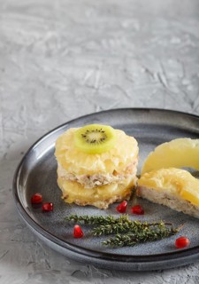 Pieces of baked pork with pineapple, cheese and kiwi on gray plate, side view, close up, selective