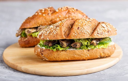 Sprats sandwiches with lettuce and cream cheese on wooden board on a gray concrete background. side
