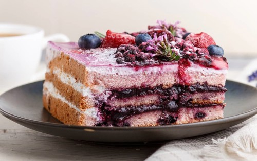 Berry cake with milk cream and blueberry jam on blue ceramic plate with cup of coffee and fresh