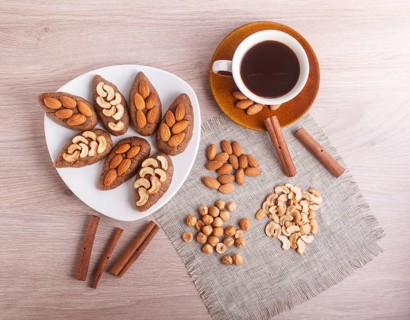 Small cakes potatoes with almonds and cashew nuts on a dessert plate. A cup of coffee, cinnamon,