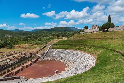 Ancient amphitheatre with rows of seats on a green meadow surrounded by hills, Ancient theatre,