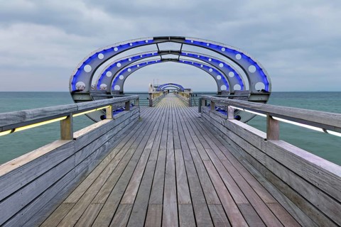 Long exposure of the Kellenhusen pier on the Baltic Sea with blue illuminated arcades