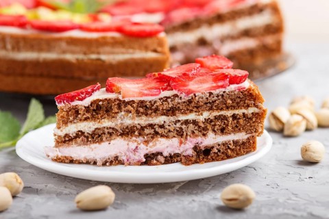 Homemade cake with yoghurt cream, strawberry, pistachio and a cup of coffee on a gray concrete