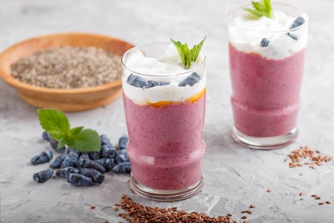 Smoothie with honeysuckle, linen and chia in a glass on gray concrete background. side view, close