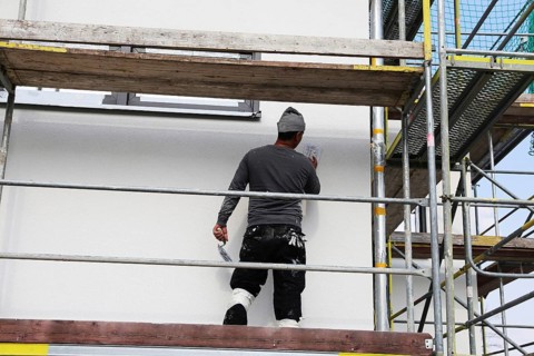 Painter and plasterer working on the facade of a new residential building (Mutterstadt development