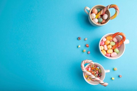 Heap of multicolored caramel candies in cups on blue pastel background. copy space, top view, flat