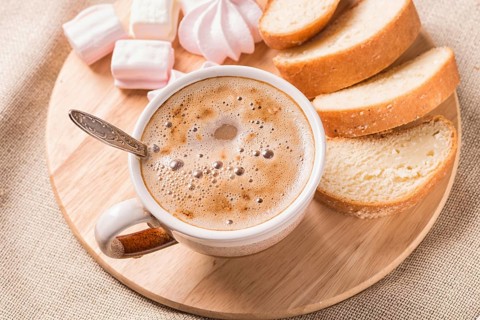Sweet buns, meringues and coffee cup on a wooden board and linen tablecloth
