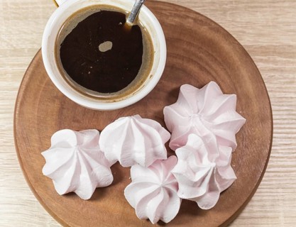 Chewing marshmallows, meringue and coffee cup on a wooden board and linen tablecloth