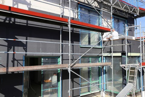 Construction workers insulate a house facade