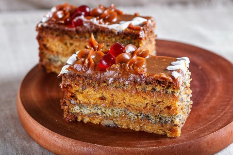 A piece of cake with caramel cream and poppy seeds on a wooden kitchen board. close up, selective