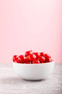 Fresh red sweet cherry in white bowl on gray and pink background. side view, close up, selective