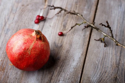 Ripe garnet with a branch on a rustic wooden background
