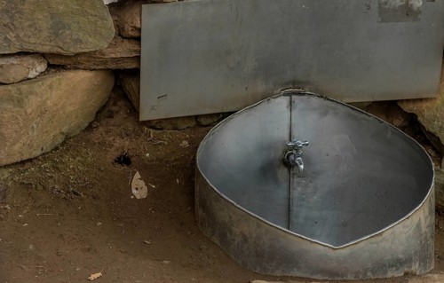 Public water faucet with metal basin located in mountain park for use by hikers visiting the area