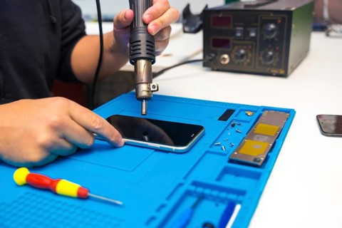 Close-up of a unrecognizable male technician fixing a mobile phone using a soldering iron in a