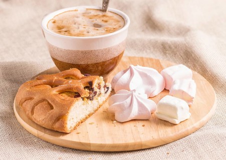 Sweet buns, meringues and coffee cup on a wooden board and linen tablecloth