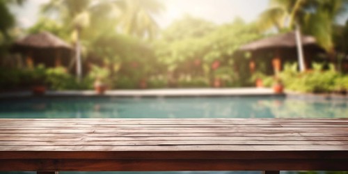 Wooden table with troical garden and swimming pool in blurry background. KI generiert, generiert AI
