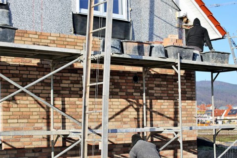 Bricklaying, clinker brick work. Bricklayers clad the facade of a detached house with clinker