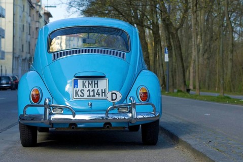 Rear of a light blue VW Volkswagen Beetle parked at the roadside, letters KMH are altered and do