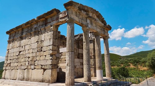 Ancient columned building in front of a blue sky with decorative clouds, Mausoleum, Heroon,