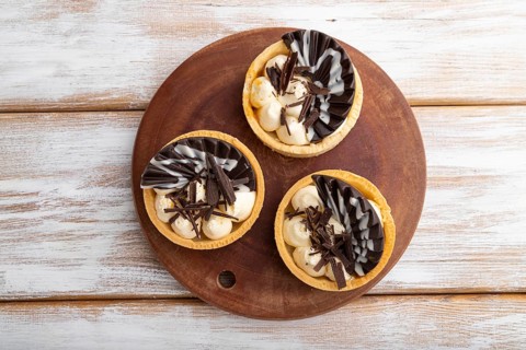 Sweet tartlets with chocolate and cheese cream on a white wooden background. top view, flat lay,