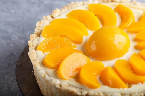 Round peach cheesecake on a gray concrete background. side view, close up