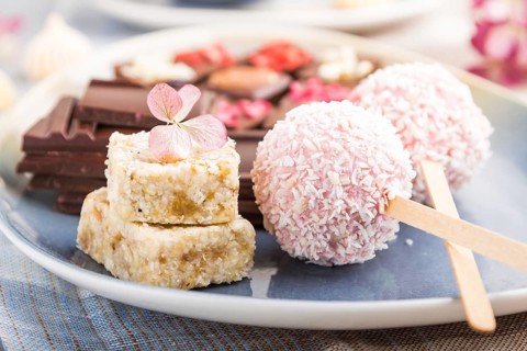 A pieces of homemade chocolate with coconut candies on a blue and brown textile. side view, close