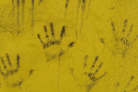 Black hand prints on side of cracked yellow wall in South Korea