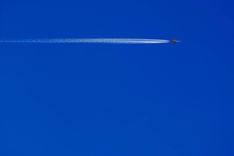 A passenger plane with vapour trail high in the blue sky