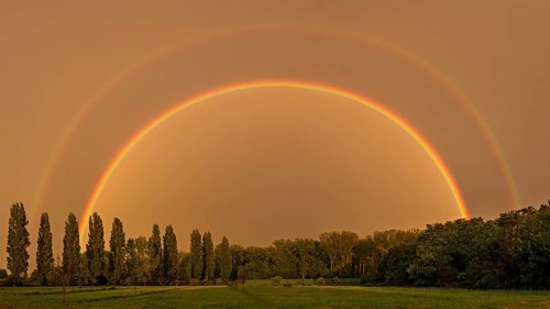 A complete and double rainbow after a thunderstorm over a cultivated landscape in the Palatinate