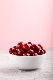 Fresh red sweet cherry in white bowl on gray and pink background. side view, close up, selective