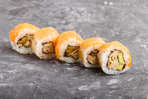 Japanese maki sushi rolls with salmon, avocado and omelette on black concrete background. Side
