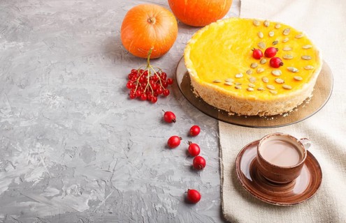 Traditional american sweet pumpkin pie decorated with hawthorn red berries and pumpkin seeds with
