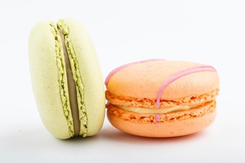 Orange and green macarons or macaroons cakes isolated on white background. side view, close up,