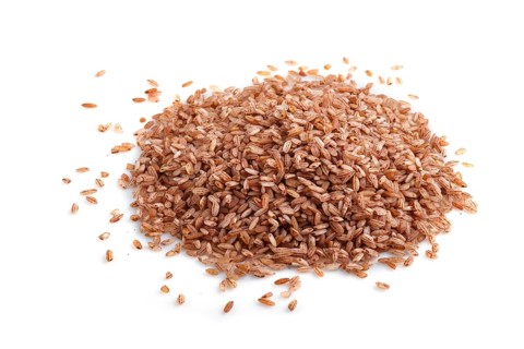 Heap of unpolished brown rice isolated on white background. Side view, flat lay, close up, macro